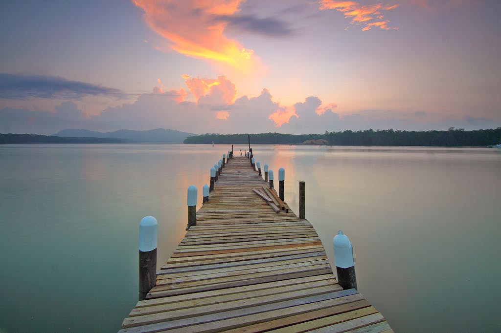 Tranquil view of a wooden pier extending into the calm lake during a breathtaking sunset.